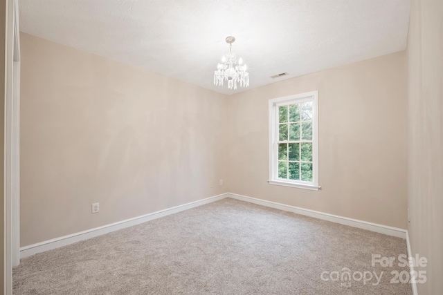 empty room with carpet flooring and a notable chandelier