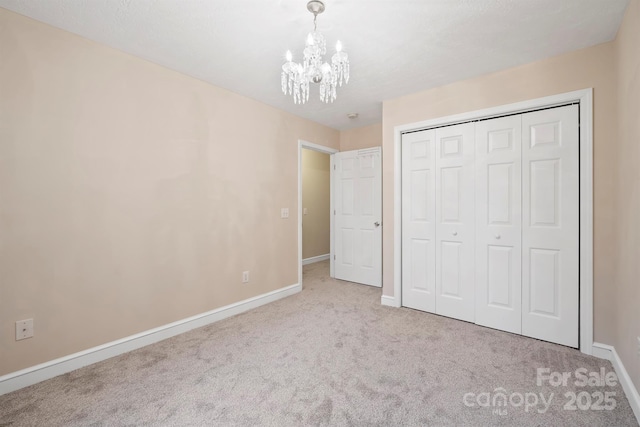 unfurnished bedroom featuring light colored carpet, an inviting chandelier, and a closet