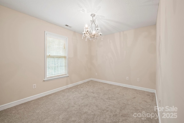 empty room featuring carpet floors and a chandelier