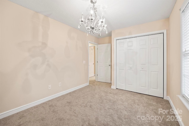 unfurnished bedroom with an inviting chandelier, multiple windows, light colored carpet, and a closet