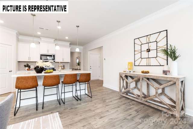 kitchen featuring white cabinetry, a kitchen breakfast bar, crown molding, pendant lighting, and appliances with stainless steel finishes