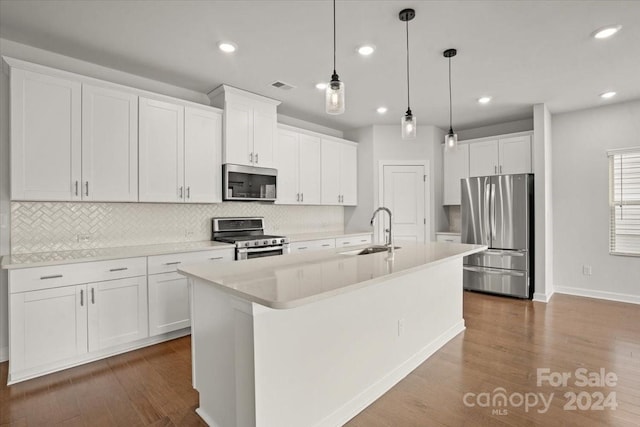 kitchen with sink, an island with sink, decorative light fixtures, white cabinets, and appliances with stainless steel finishes