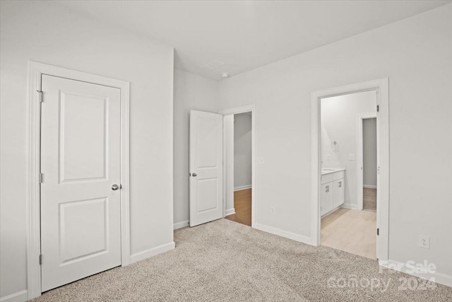 unfurnished bedroom featuring ensuite bathroom and light colored carpet