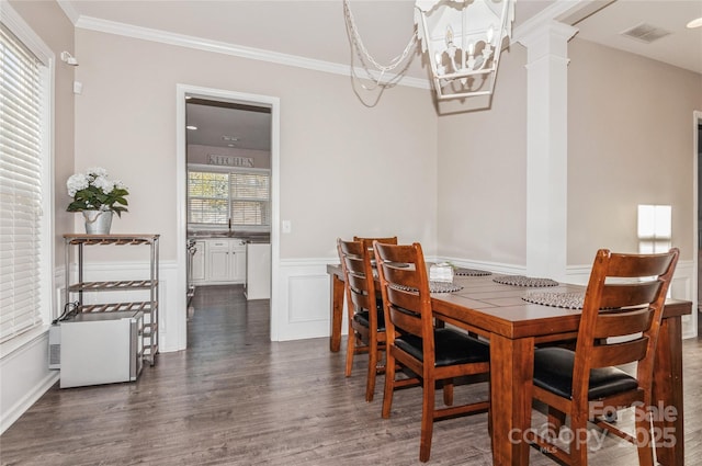 dining area with ornate columns, ornamental molding, a chandelier, and dark hardwood / wood-style floors