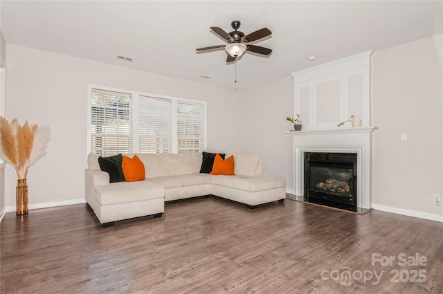 living room featuring dark wood-type flooring, ceiling fan, and a fireplace