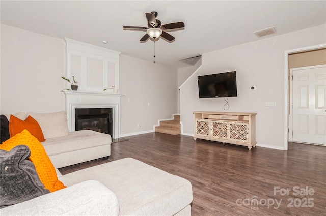 living room featuring dark wood-type flooring, ceiling fan, and a fireplace