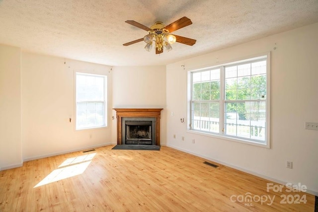 unfurnished living room with ceiling fan, light wood-type flooring, and a textured ceiling