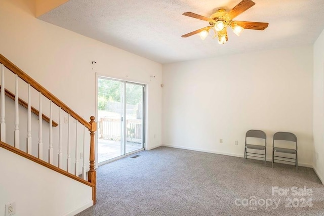 interior space with a textured ceiling, light colored carpet, and ceiling fan