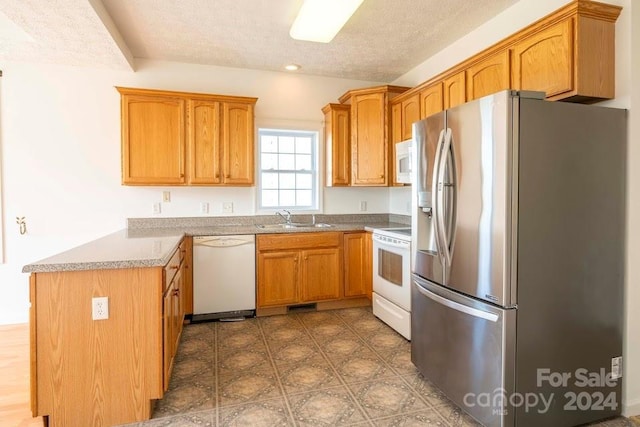 kitchen with a textured ceiling, white appliances, and sink