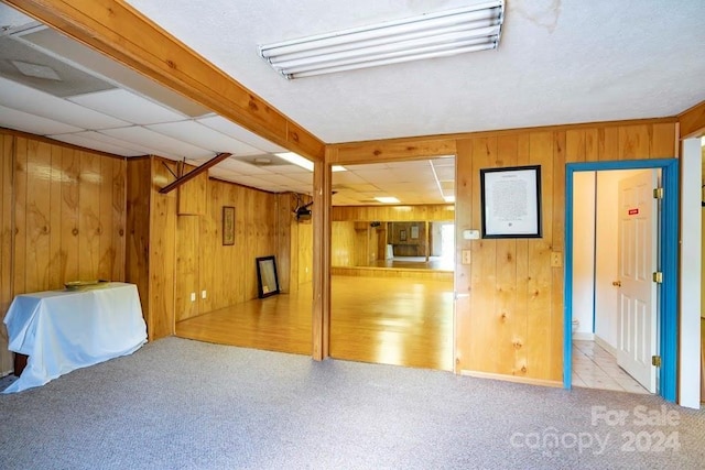 basement featuring wooden walls and light colored carpet