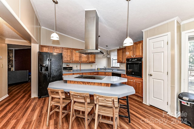 kitchen featuring crown molding, decorative light fixtures, island range hood, a kitchen island, and black appliances