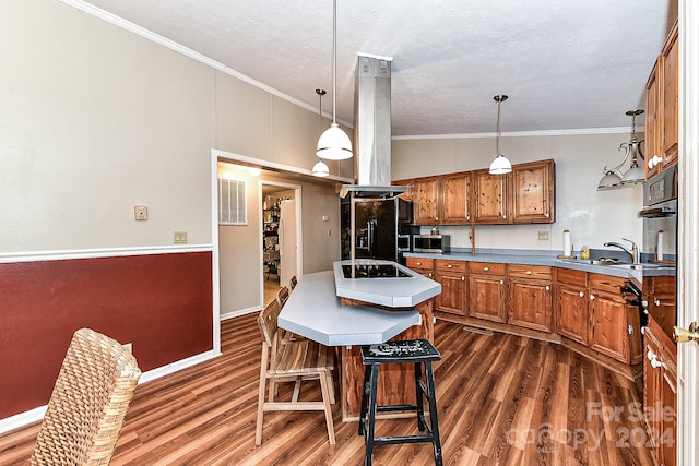 kitchen featuring island exhaust hood, a breakfast bar, sink, black appliances, and pendant lighting