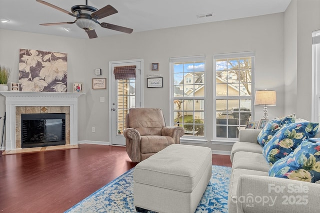 living room with a wealth of natural light, a fireplace, ceiling fan, and wood-type flooring