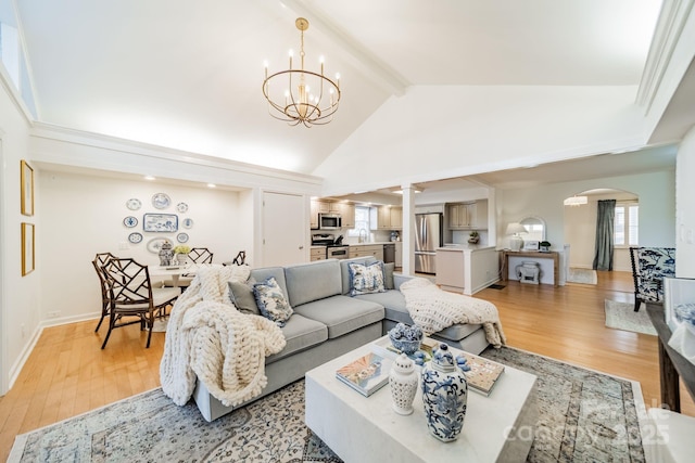 living room featuring vaulted ceiling with beams, light hardwood / wood-style flooring, and an inviting chandelier