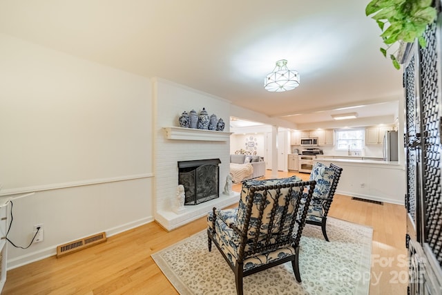 dining area featuring light hardwood / wood-style floors and a brick fireplace