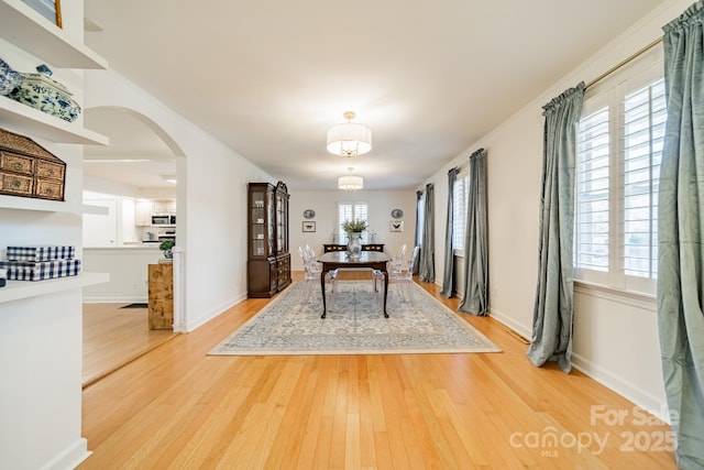 dining area with light wood-type flooring, plenty of natural light, and crown molding