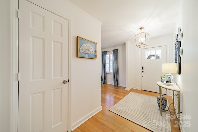 foyer with hardwood / wood-style flooring, an inviting chandelier, and ornamental molding