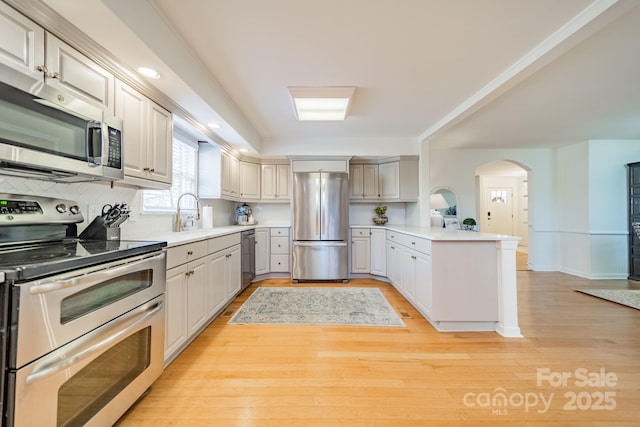 kitchen featuring sink, kitchen peninsula, stainless steel appliances, and light hardwood / wood-style flooring