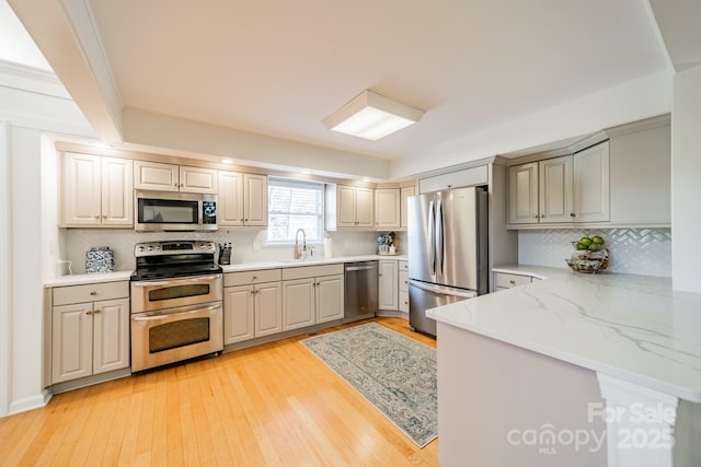 kitchen with backsplash, kitchen peninsula, stainless steel appliances, and light hardwood / wood-style floors