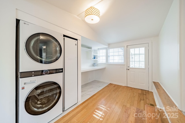 laundry room featuring stacked washing maching and dryer and light wood-type flooring