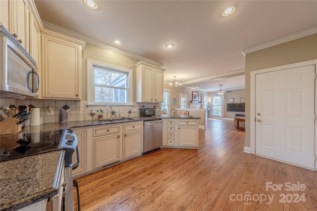 kitchen featuring sink, stainless steel appliances, crown molding, cream cabinets, and decorative light fixtures