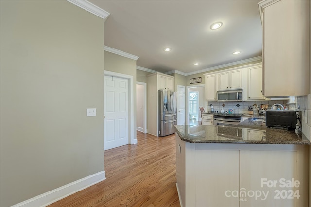 kitchen with kitchen peninsula, dark stone counters, decorative backsplash, appliances with stainless steel finishes, and ornamental molding