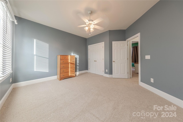 unfurnished bedroom featuring multiple windows, a closet, ceiling fan, and light colored carpet