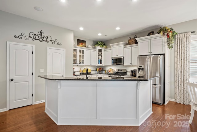 kitchen featuring appliances with stainless steel finishes, white cabinetry, a large island with sink, and dark wood-type flooring