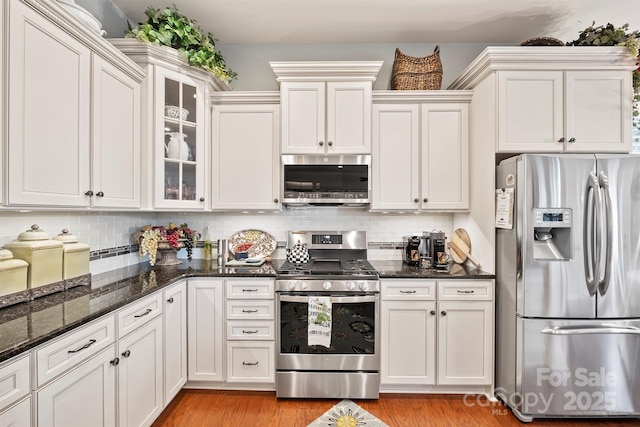 kitchen with dark stone counters, white cabinetry, tasteful backsplash, and stainless steel appliances