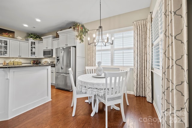 kitchen featuring stainless steel appliances, dark hardwood / wood-style floors, white cabinets, a chandelier, and hanging light fixtures