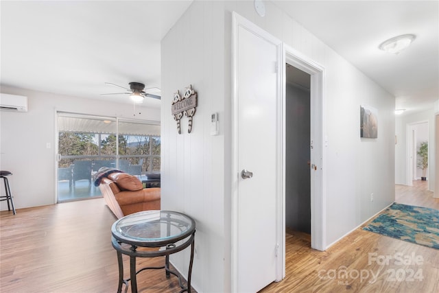 corridor featuring light wood-type flooring and a wall unit AC