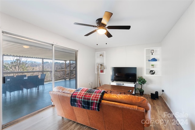 living room featuring hardwood / wood-style flooring, built in shelves, and ceiling fan