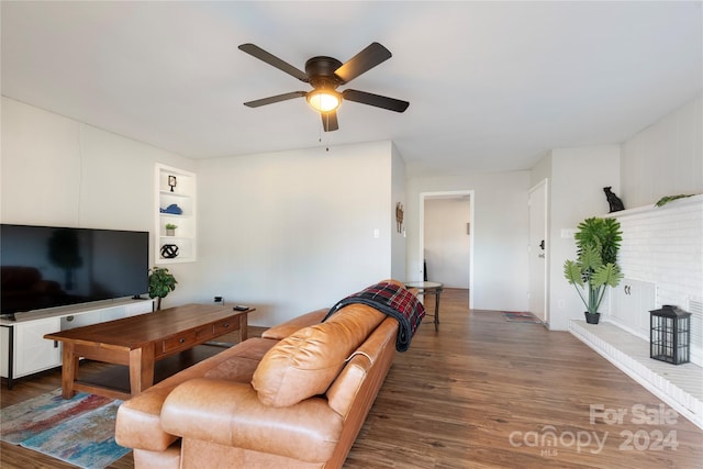 living room featuring built in shelves, dark hardwood / wood-style floors, and ceiling fan