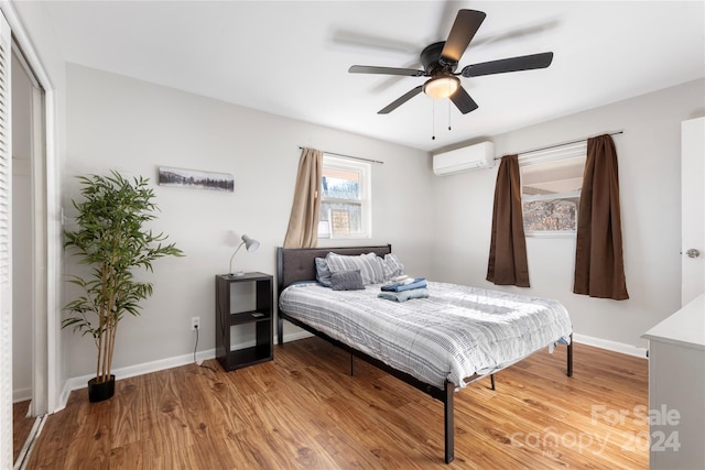 bedroom featuring a wall mounted air conditioner, hardwood / wood-style flooring, and ceiling fan