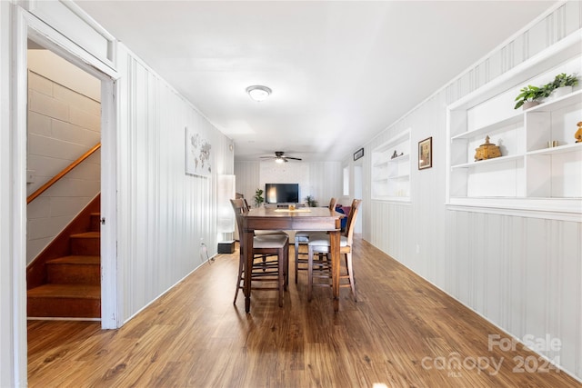 dining space featuring built in shelves, ceiling fan, and hardwood / wood-style floors