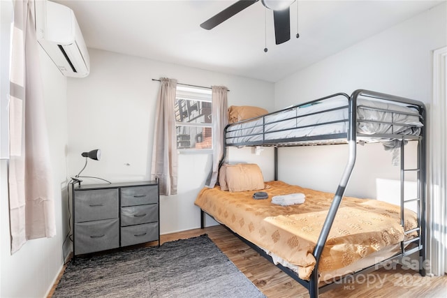 bedroom featuring dark hardwood / wood-style floors, a wall mounted AC, and ceiling fan