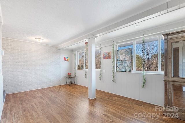 empty room with hardwood / wood-style floors and brick wall