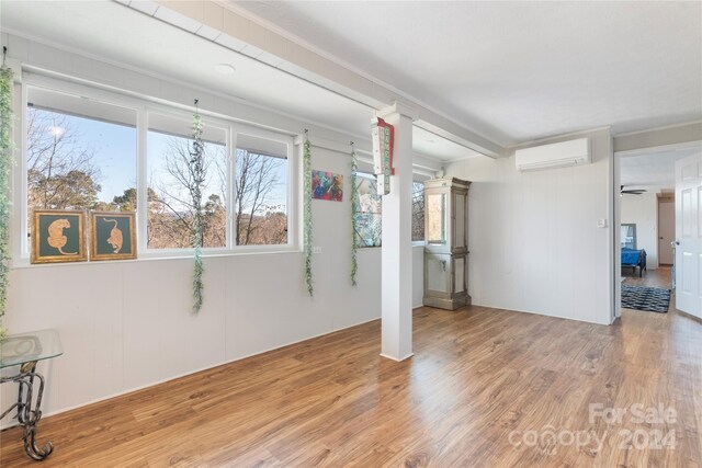 unfurnished room with a wall unit AC and light hardwood / wood-style floors