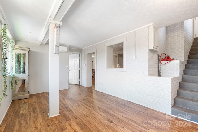 unfurnished living room featuring crown molding, brick wall, and hardwood / wood-style flooring