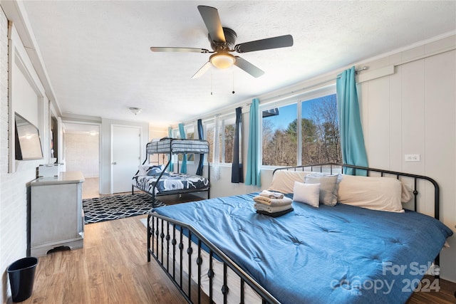 bedroom with a textured ceiling, light hardwood / wood-style flooring, ceiling fan, and ornamental molding