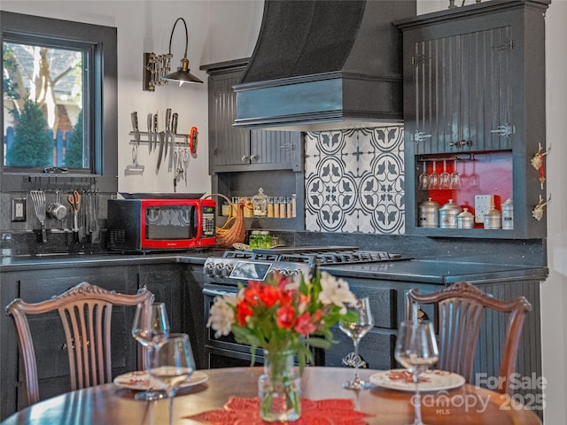 kitchen with stainless steel range and custom range hood