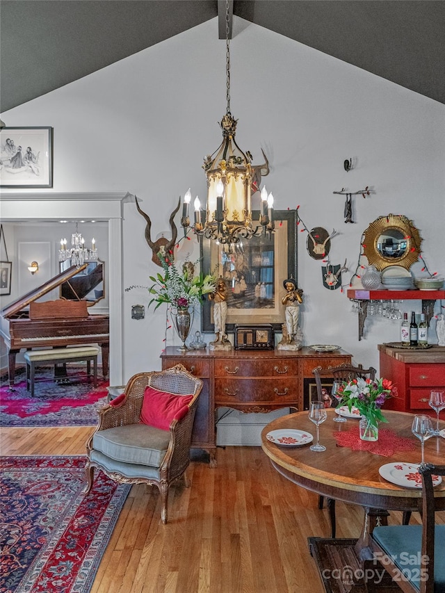 dining area featuring vaulted ceiling with beams, wood-type flooring, and an inviting chandelier