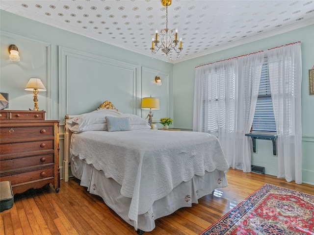 bedroom featuring a chandelier, light hardwood / wood-style flooring, and crown molding