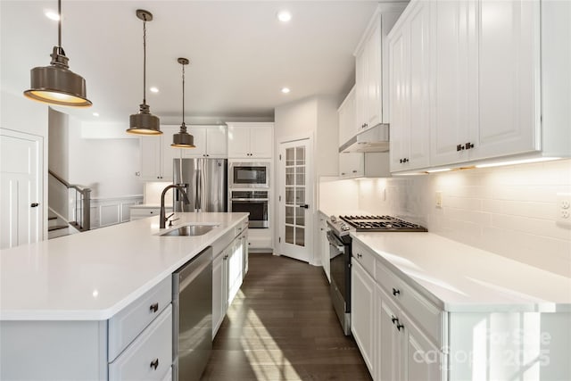 kitchen with sink, stainless steel appliances, white cabinets, a center island with sink, and decorative light fixtures