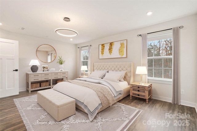 bedroom with multiple windows and dark wood-type flooring