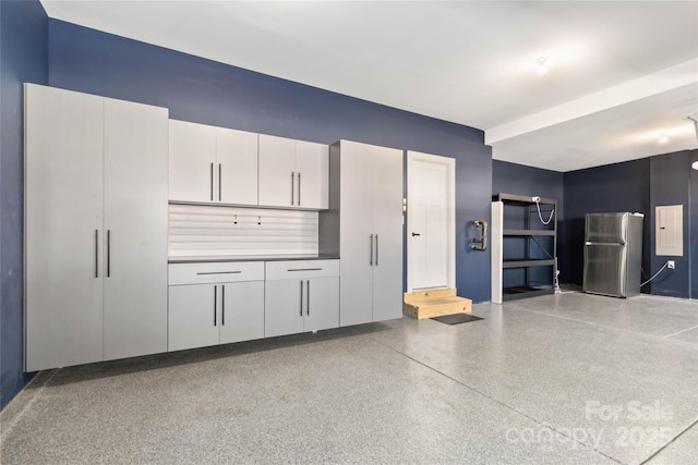 garage featuring electric panel and stainless steel refrigerator