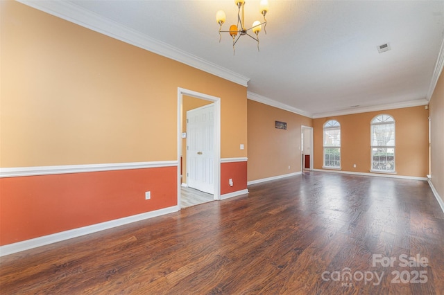 empty room featuring an inviting chandelier, wood finished floors, baseboards, and ornamental molding