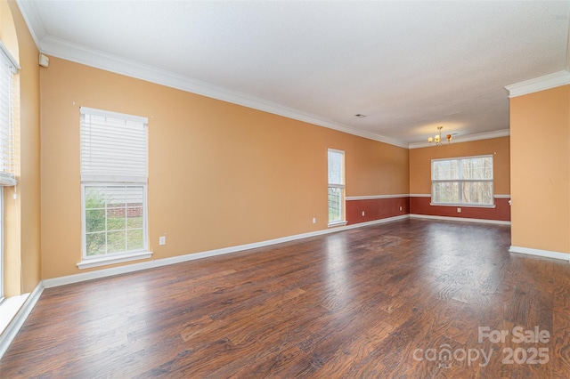 unfurnished room with plenty of natural light, an inviting chandelier, wood finished floors, and crown molding