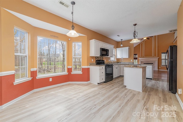 kitchen with light wood-type flooring, visible vents, black appliances, and white cabinetry