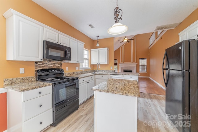 kitchen featuring visible vents, black appliances, white cabinets, and a center island